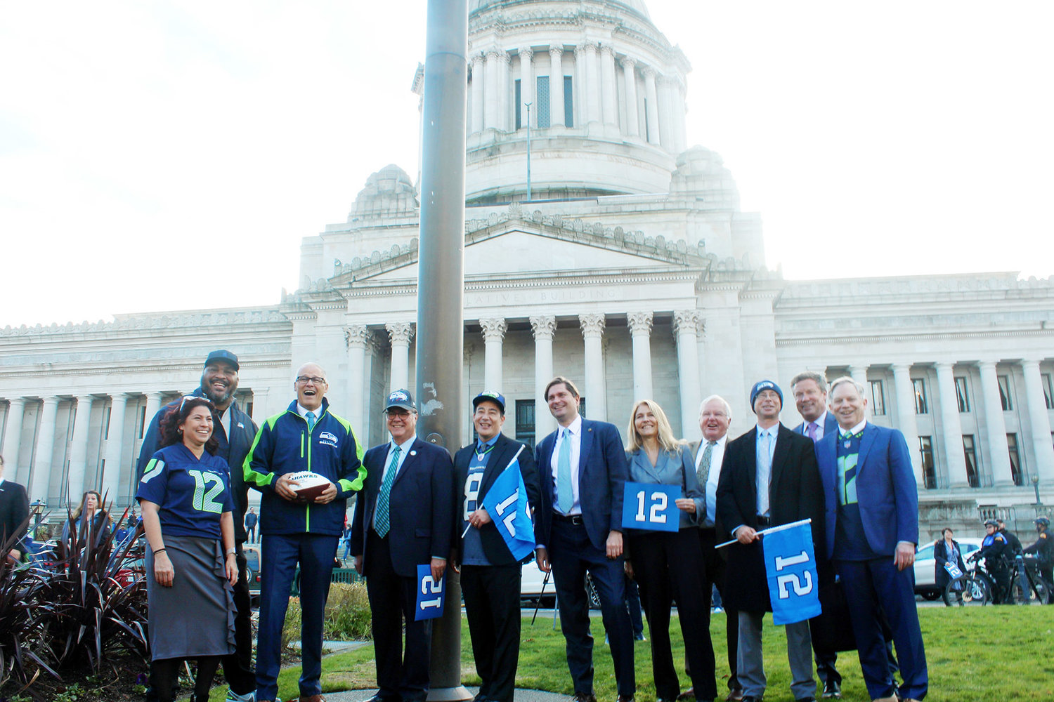 Gov. Jay Inslee, Secretary of State Steve Hobbs and other Washington lawmakers stand in front of the legislative building with Seahawks star Walter Jones after raising the 12th-man flag Jan. 11.